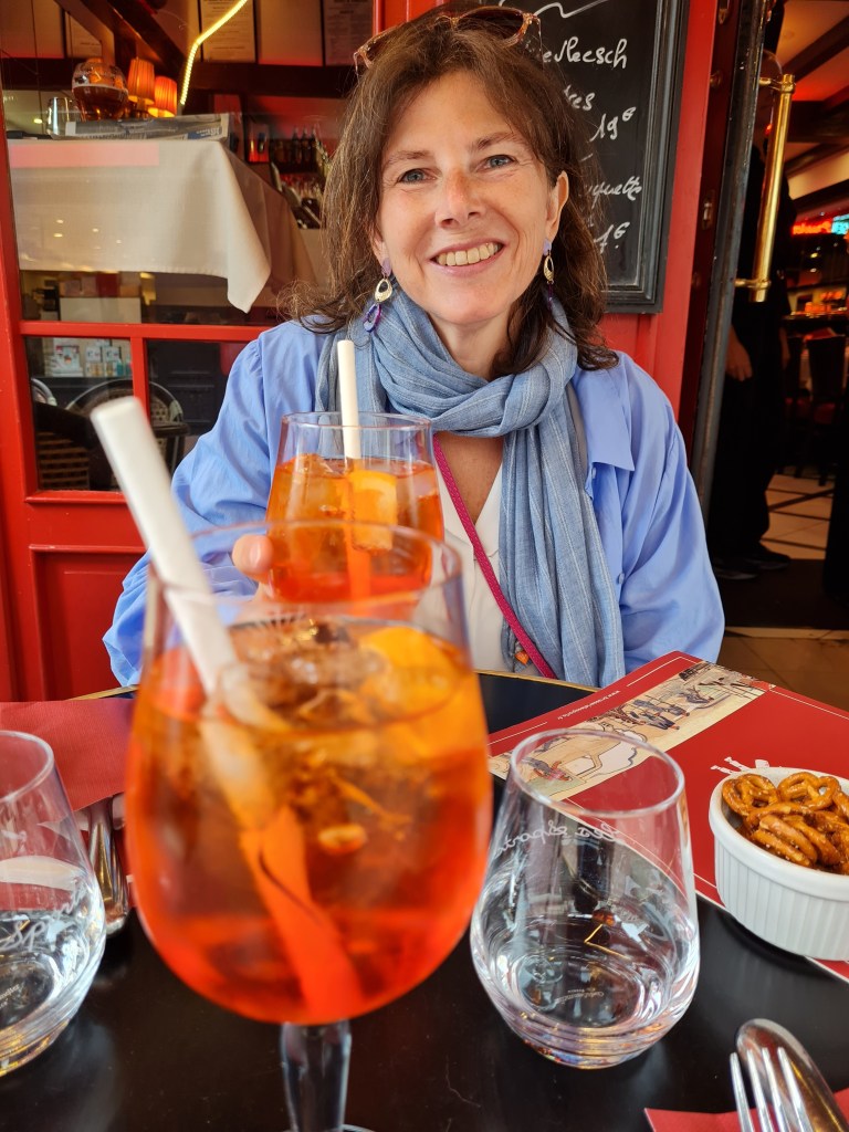 woman having aperol spritz and smiling at camera